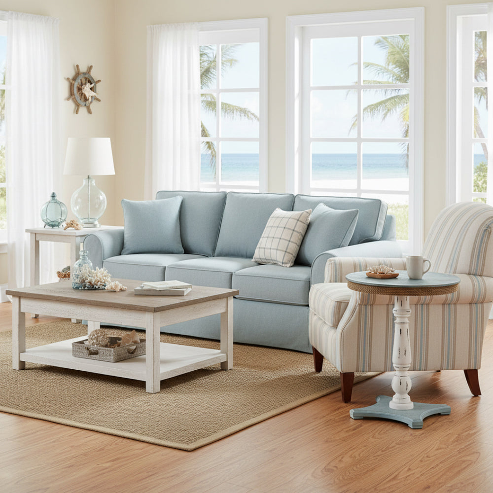 Living room with light blue sofa, striped armchair, and coffee table near large windows with a view of palm trees.