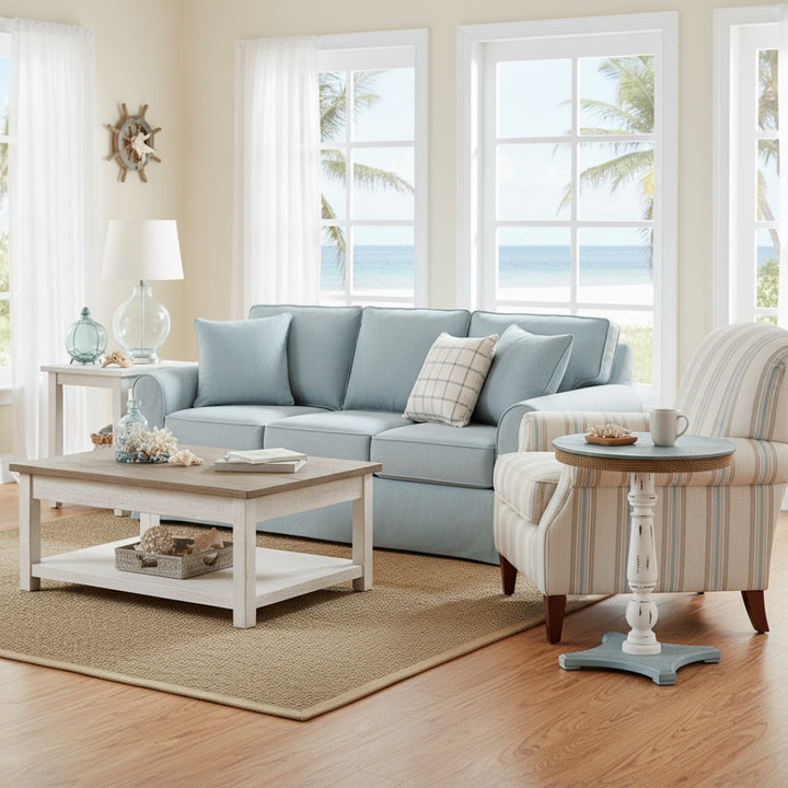 Living room with light blue sofa, striped armchair, and coffee table near large windows with a view of palm trees.