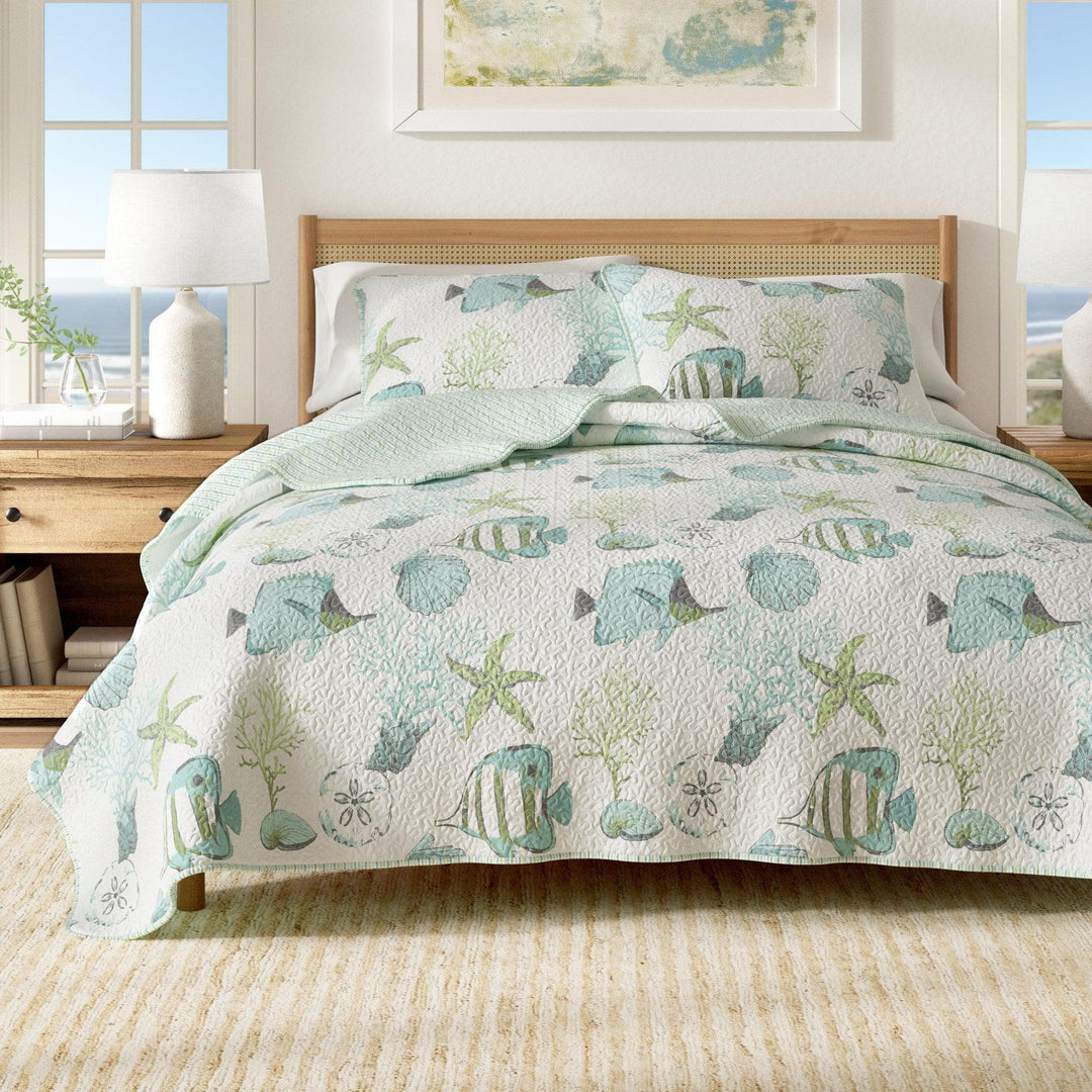 Bed with a sea-themed quilt in a bright bedroom. Coastal Compass Home Decor