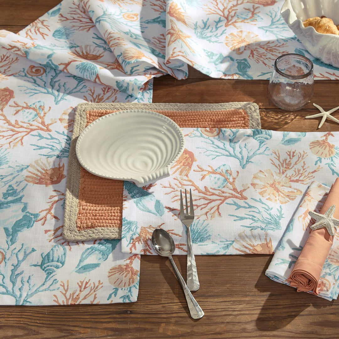 Seaside Treasures coastal table linen collection with matching table runner, placemat, and napkin in a seashell and coral pattern.