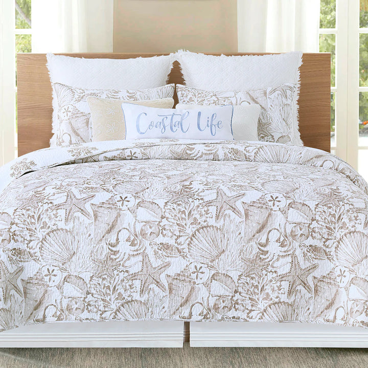 Shoreline Treasures Quilt Set featuring beige seashells and starfish paired with white pillows and a white and blue "coastal life" throw pillow