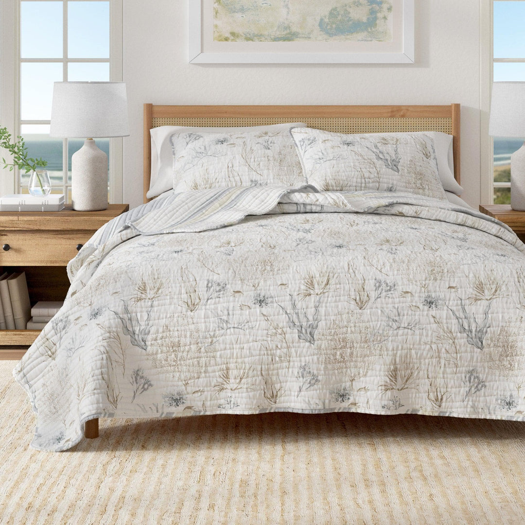 Shoreline Meadows Quilt set with floral-patterned bedding in a bright room with large windows.