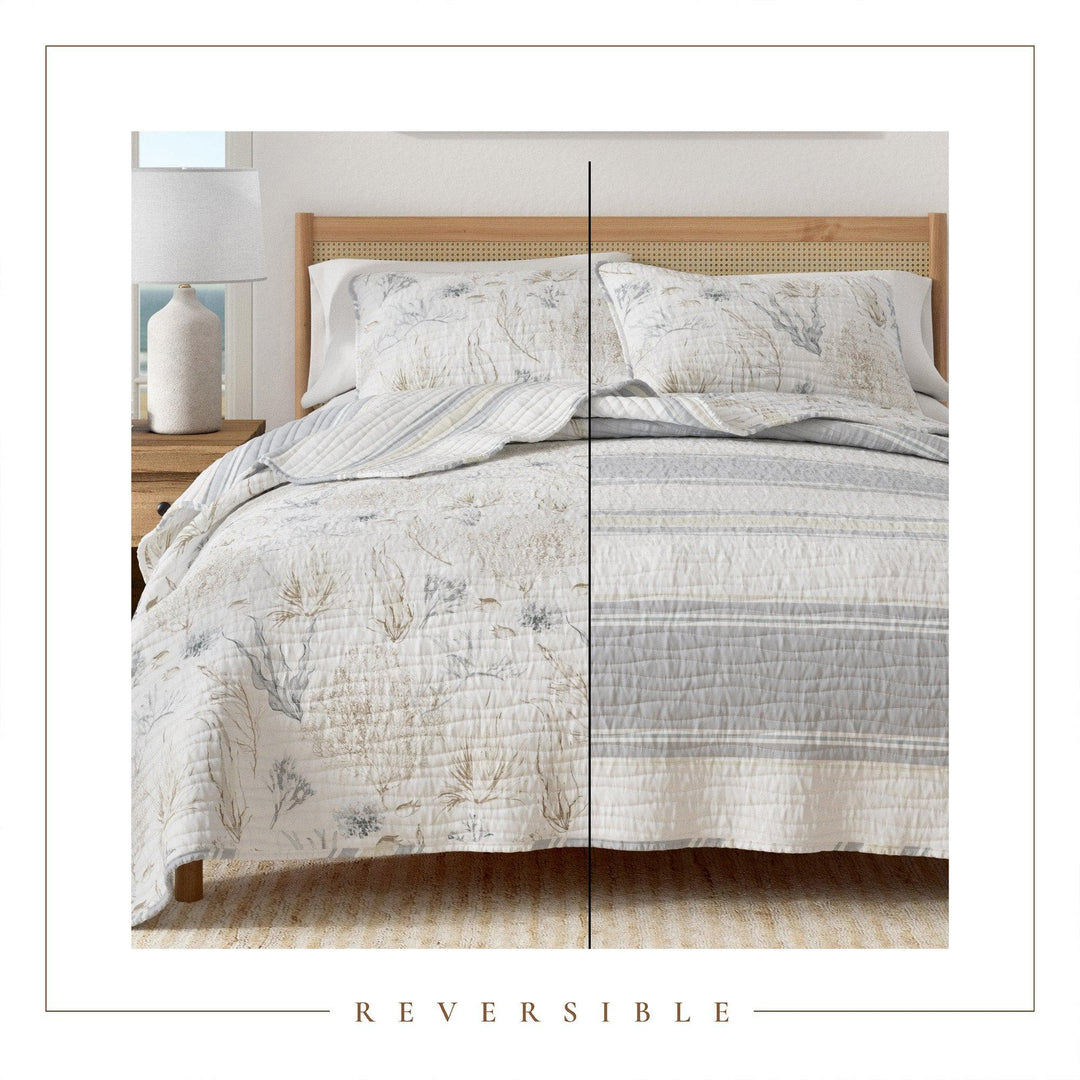 Reversible Shoreline Meadows quilt set on a bed with a wooden headboard and nightstand.
