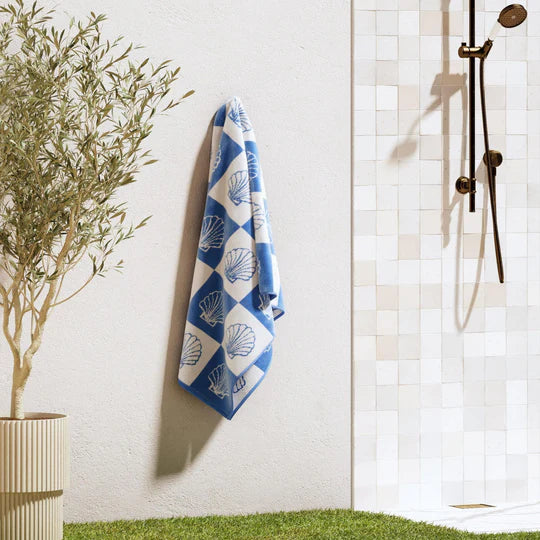 Blue and white checkered seashell beach towel hanging in coastal bathroom setting