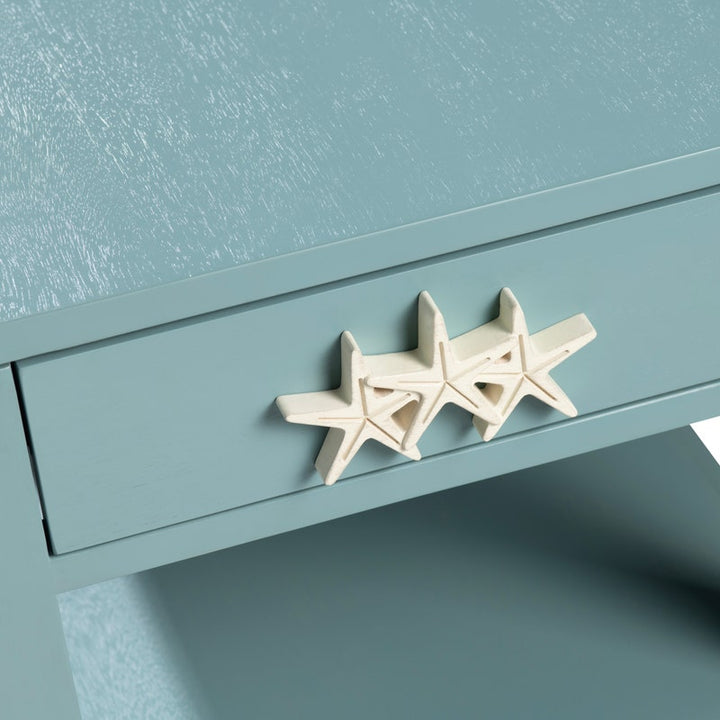 A close-up of a light blue drawer with three cream-colored starfish-shaped hardware pulls attached to the front.