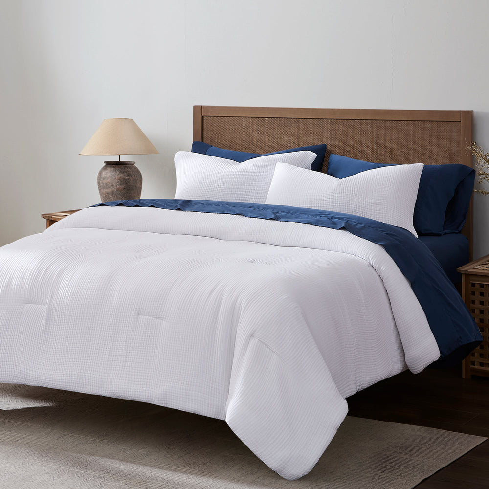 Voile comforter set in while with dark blue sheets and pillow cases on a brown wooden bed
