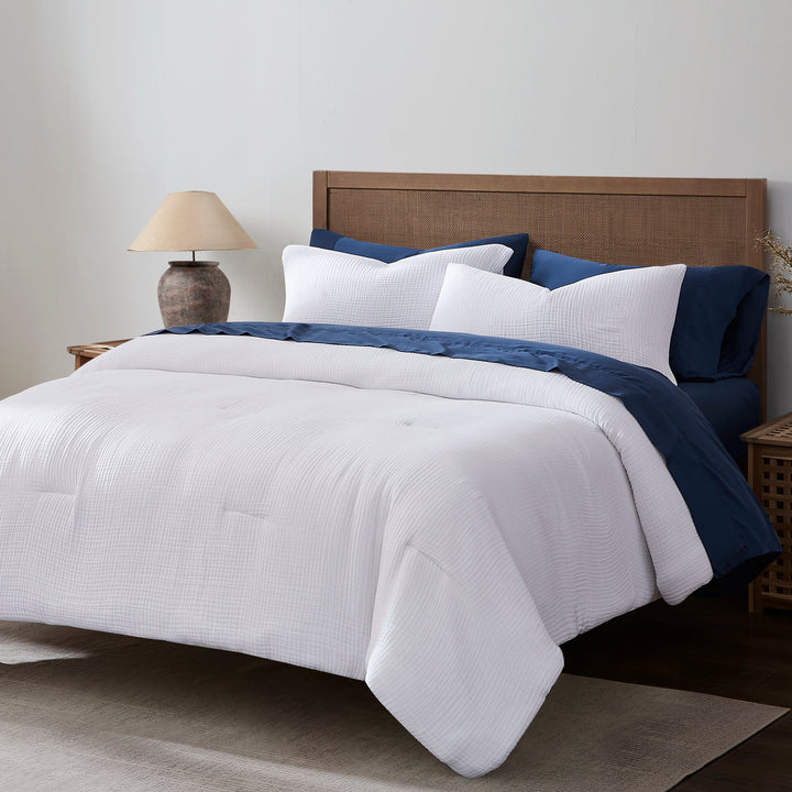 Voile comforter set in while with dark blue sheets and pillow cases on a brown wooden bed