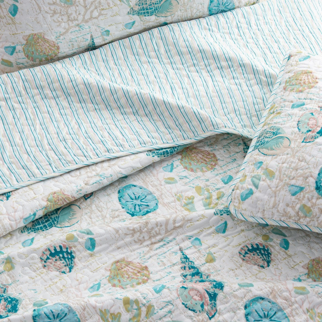 West Sands Reversible quilt set featuring reverse blue and tan stripe pattern folded over the blue seashell  pattern design