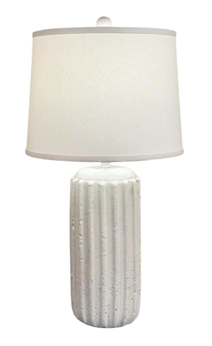 Table lamp with textured white base and white shade on a white background