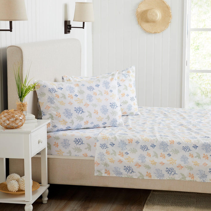 Coral reef patterned bedding set on a bed in a well-lit bedroom.