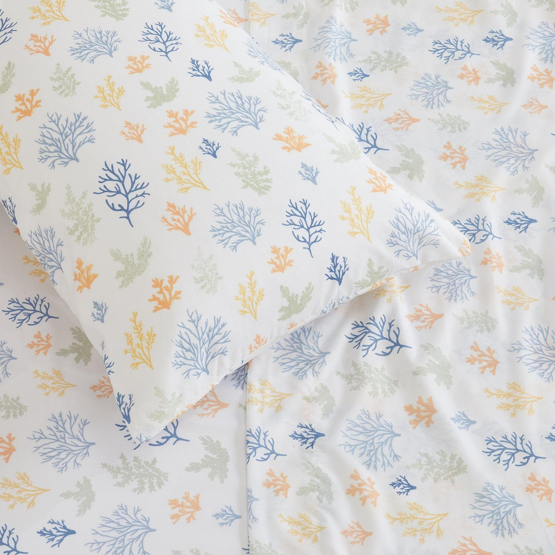 Fabric with a pattern of blue, green, and orange leaves on a white background