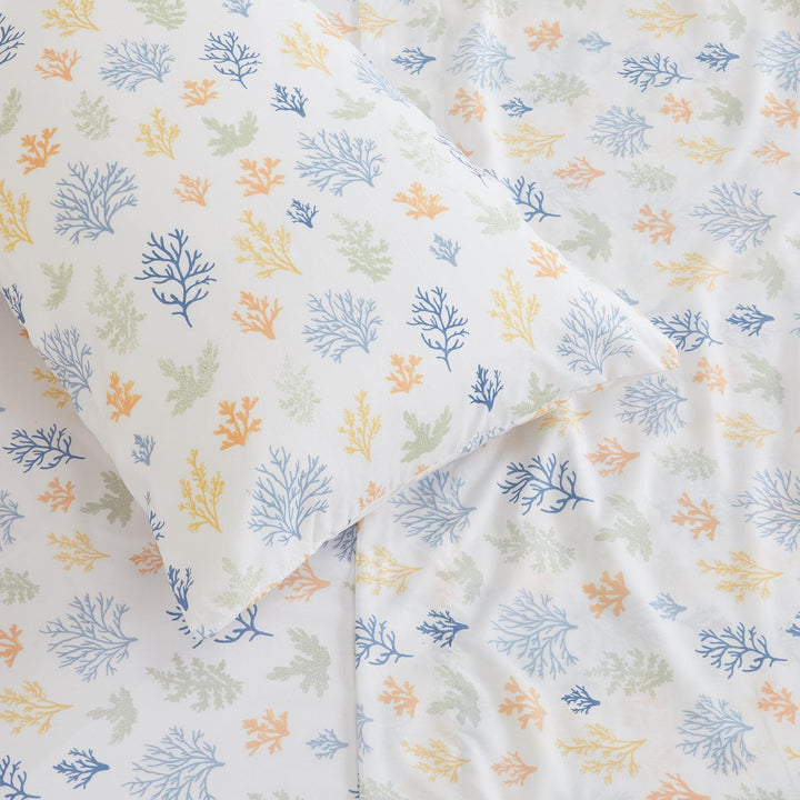Fabric with a pattern of blue, green, and orange leaves on a white background