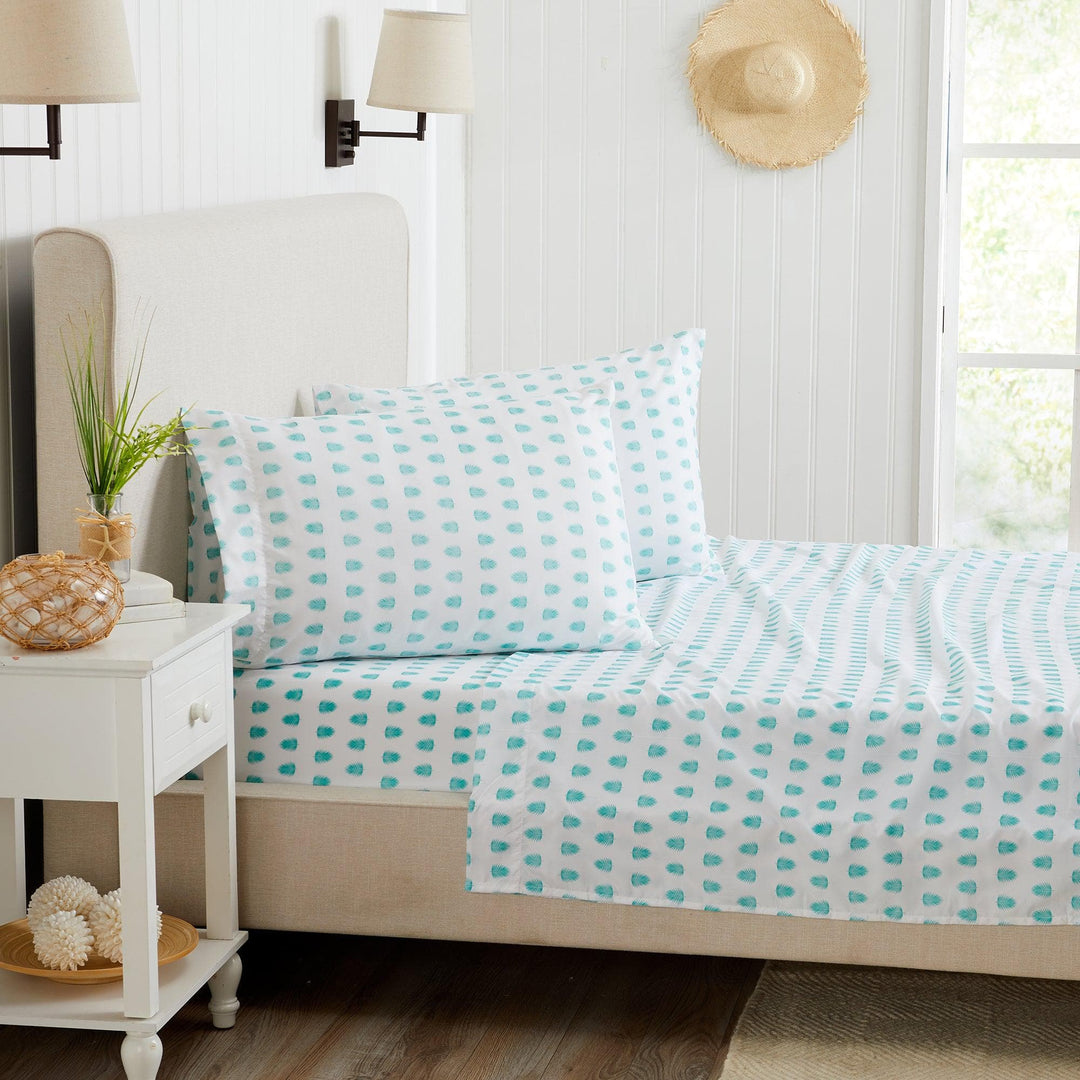 Bed with turquoise tropical leaf patterned bedding in a bright bedroom