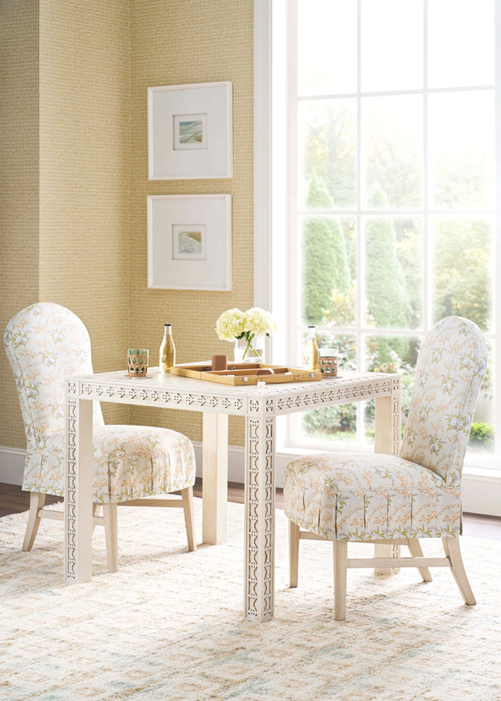 Dining room with a white table and chairs against a yellow wall with framed pictures.