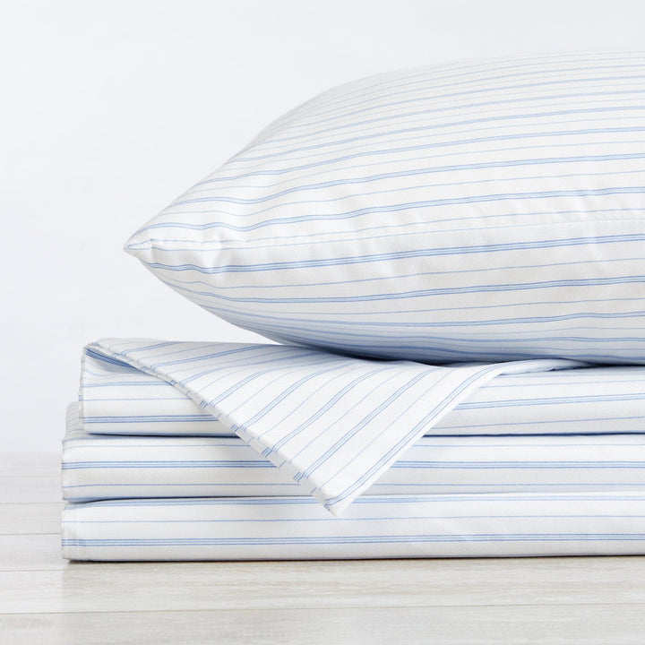 Stack of blue striped bed sheets and pillowcase on a white background