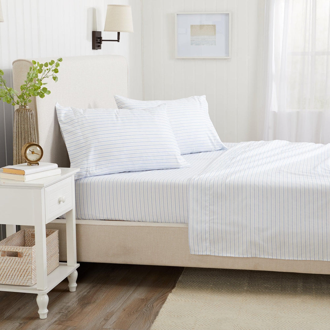 Neatly made bed with striped bedding in a bedroom setting.