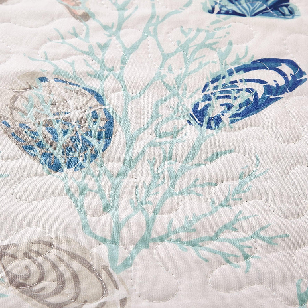 Close-up of a quilt with blue and gray shell patterns on white