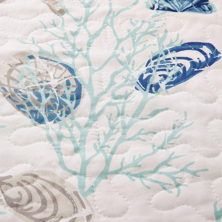 Close-up of a quilt with blue and gray shell patterns on white