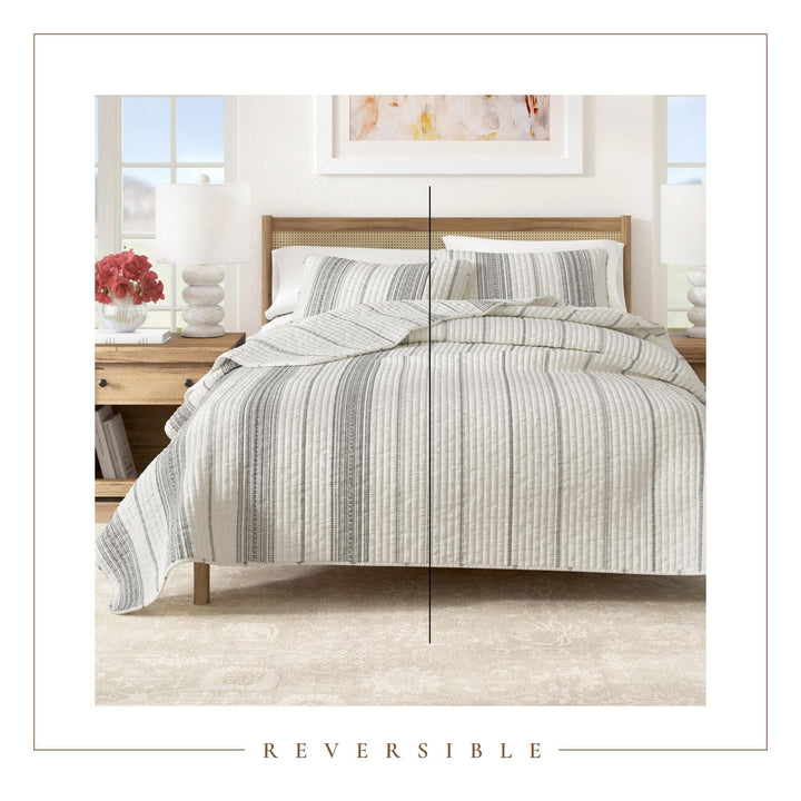 Bed with grey striped duvet and pillows in a bedroom setting, with 'Reversible' text at the bottom.