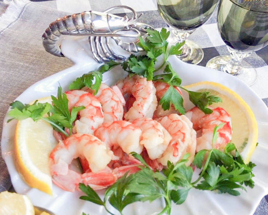 Plated shrimp with lemon wedges and parsley on a checkered tablecloth.