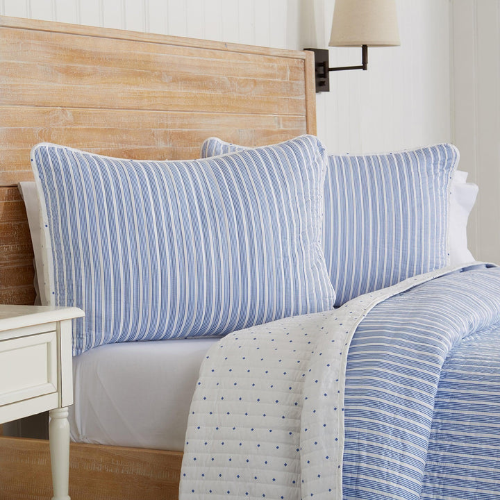 Bed with blue striped pillows and a wooden headboard
