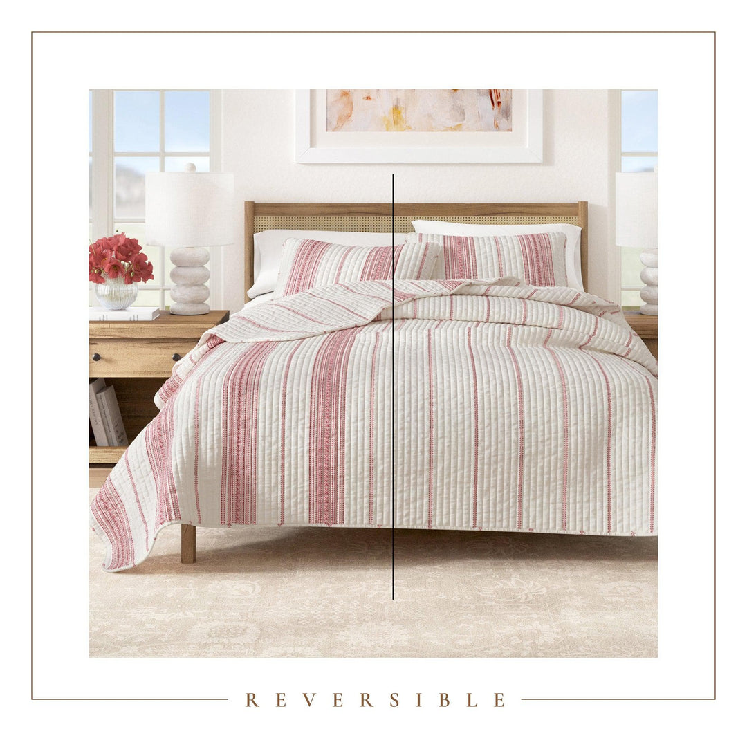 Bed with red striped bedding in a bedroom setting, featuring the word 'Reversible'.