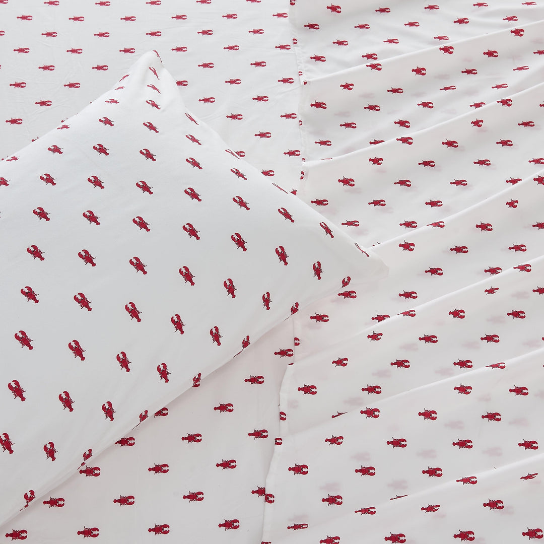 White sheets and pillow case with red lobster pattern.