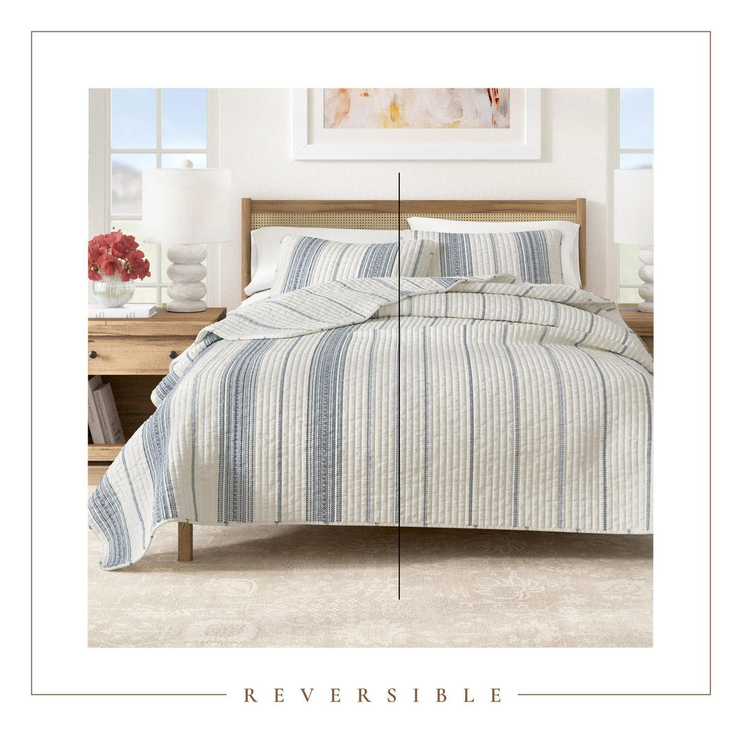Striped bedding set on a bed in a bedroom with 'Reversible' text at the bottom.