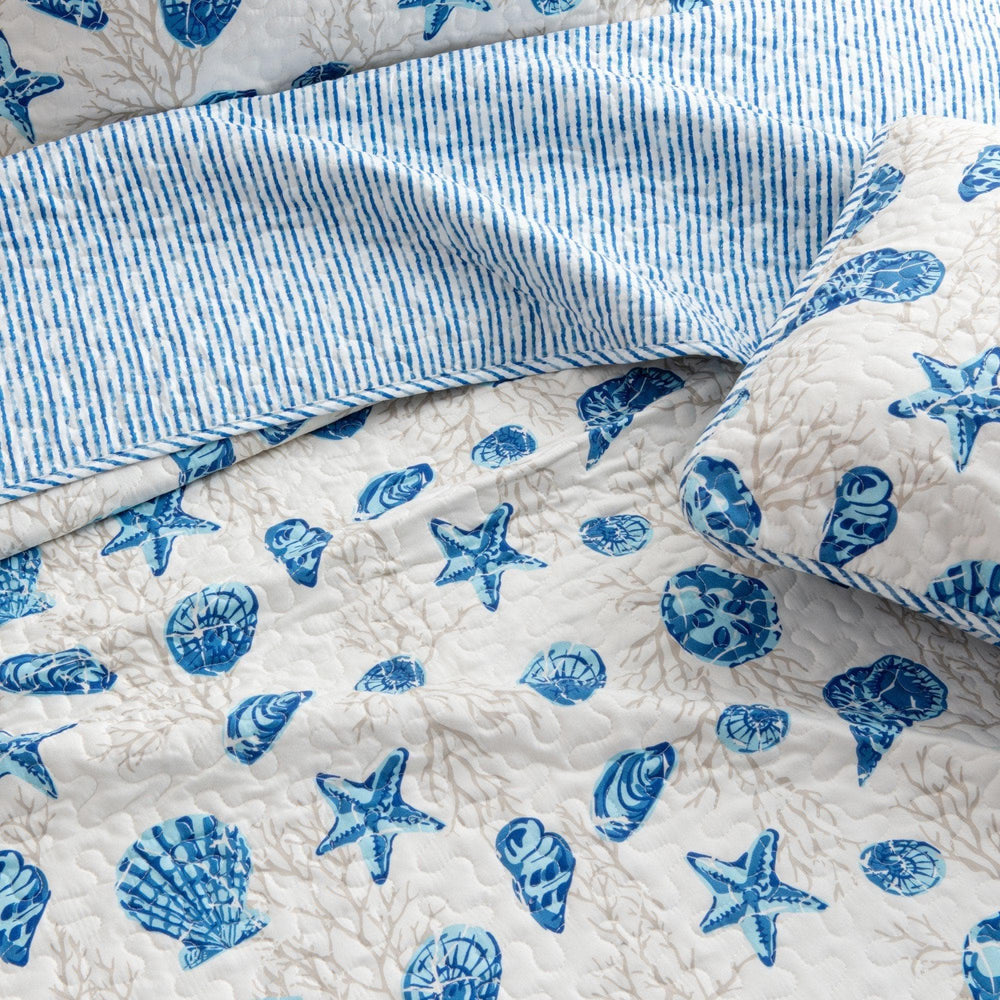 Quilt with blue starfish and shell patterns on a white background