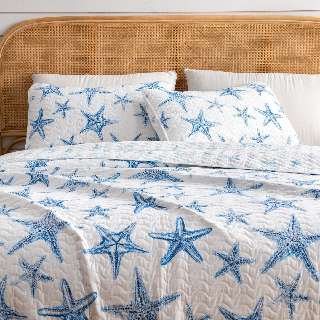 Bed with blue starfish patterned bedding on a wooden headboard.
