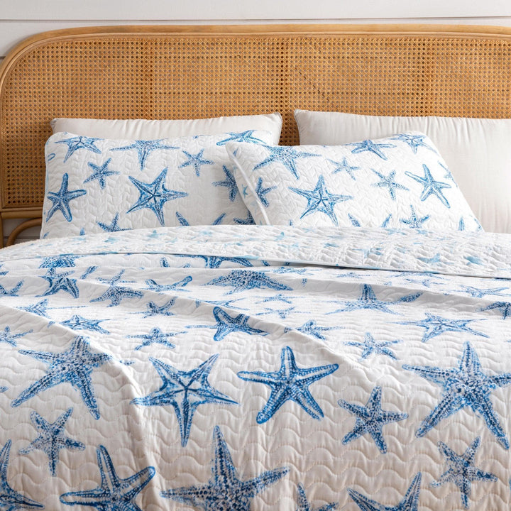 Bed with blue starfish patterned bedding on a wooden headboard.