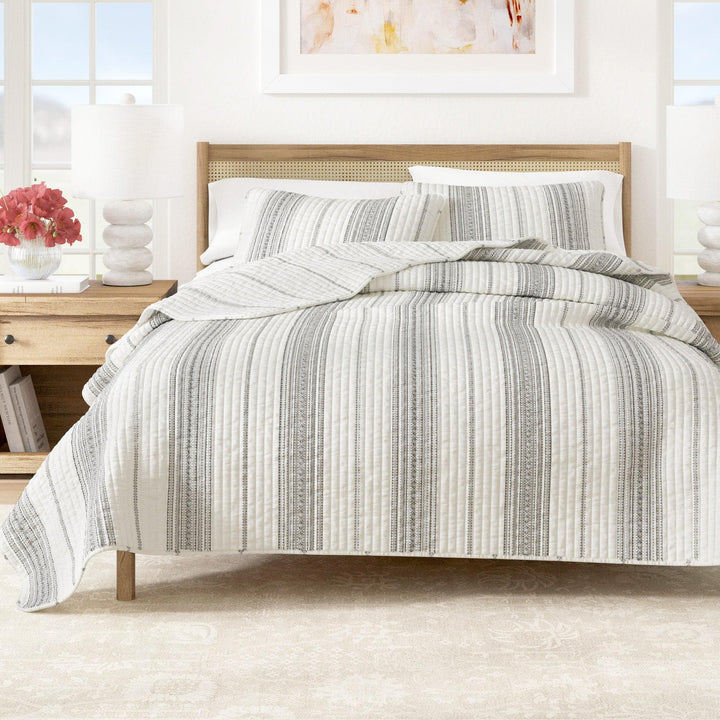 Striped comforter set on a bed in a bright bedroom with decor elements.