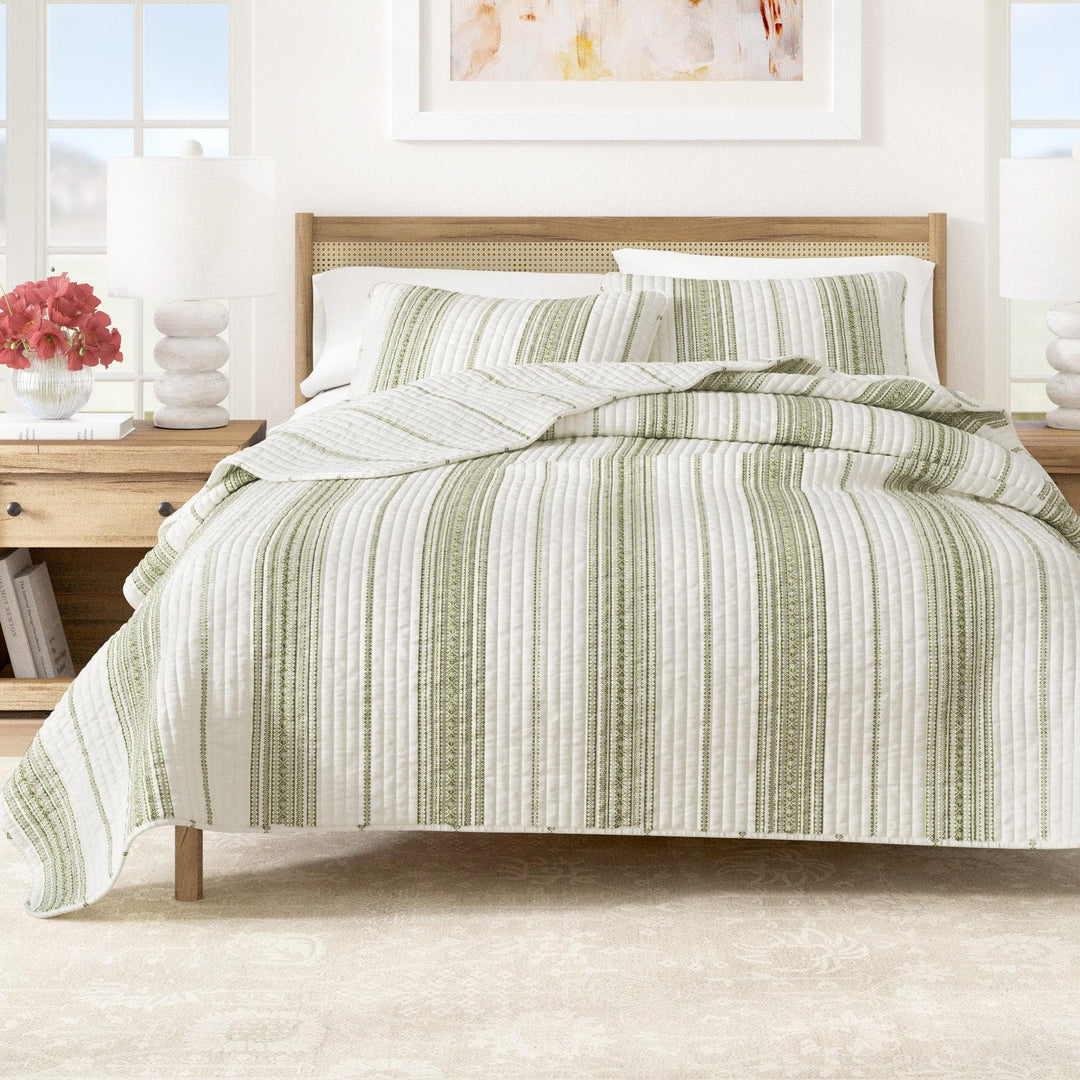 Bed with green and white striped bedding in a bright bedroom setting.