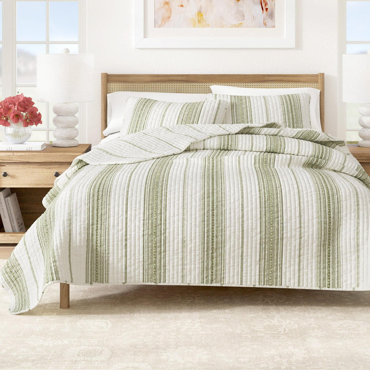 Bed with green and white striped bedding in a bright bedroom setting.