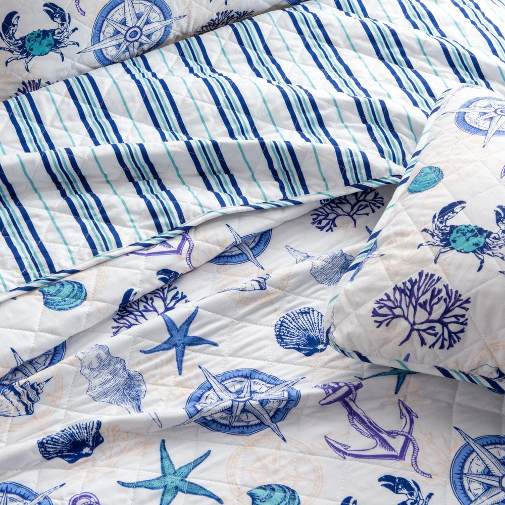 Nautical-themed quilt with blue and white patterns featuring anchors, stars, and compasses.