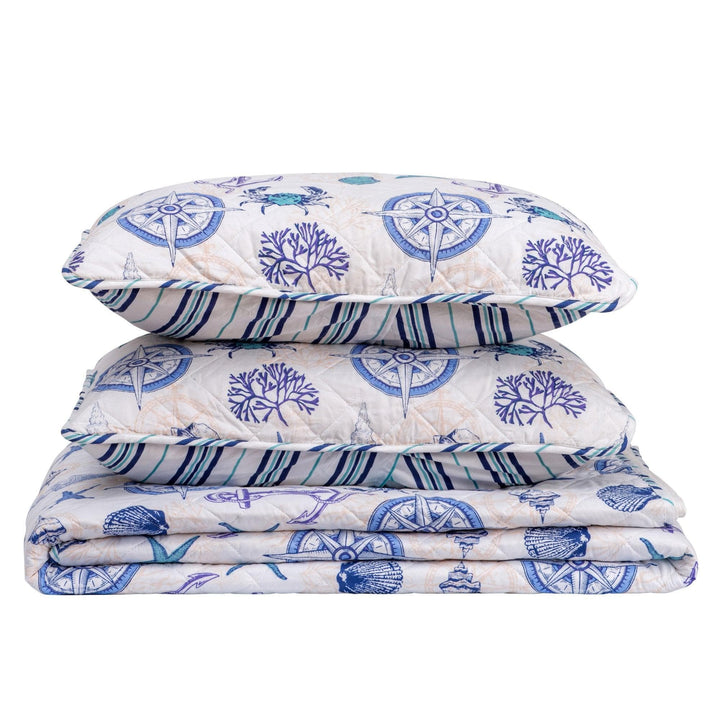 Set of folded bedding with blue and white coastal patterns on a white background