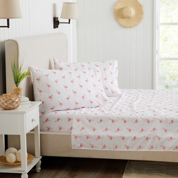 Bed with flamingo patterned bedding in a bright bedroom setting