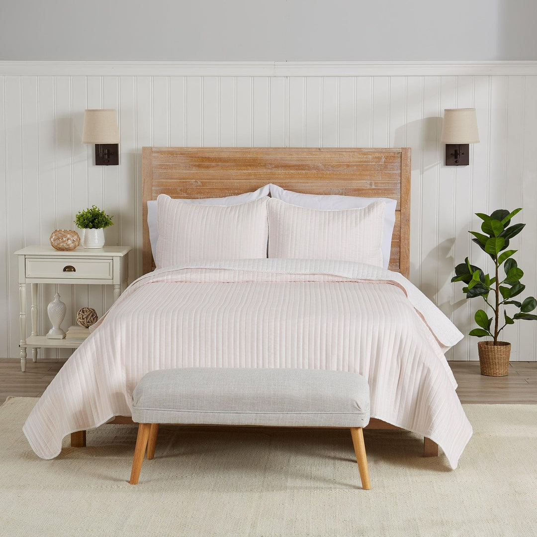 Neatly made bed with white bedding in a bedroom setting.