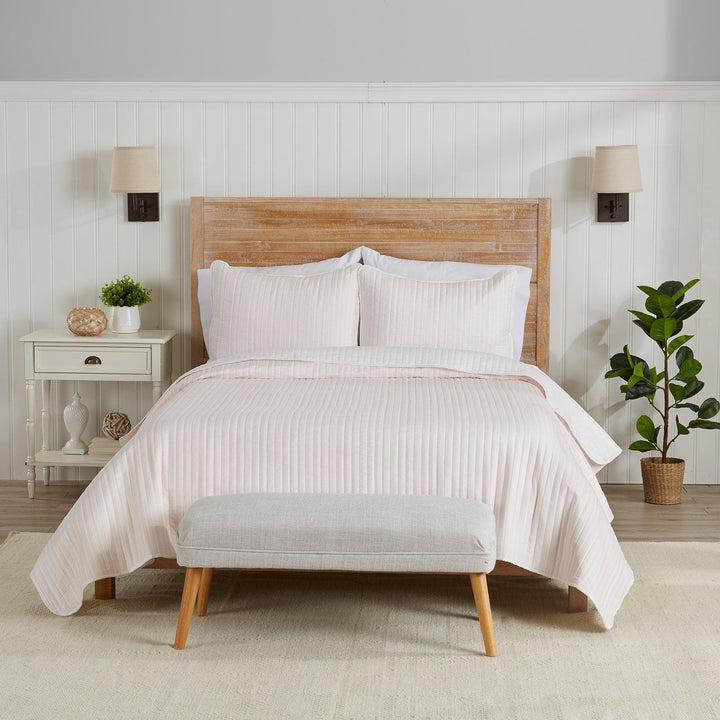 Neatly made bed with white bedding in a bedroom setting.
