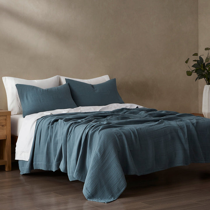 Bed with voile cotton blanket set bedding and pillows against a beige wall