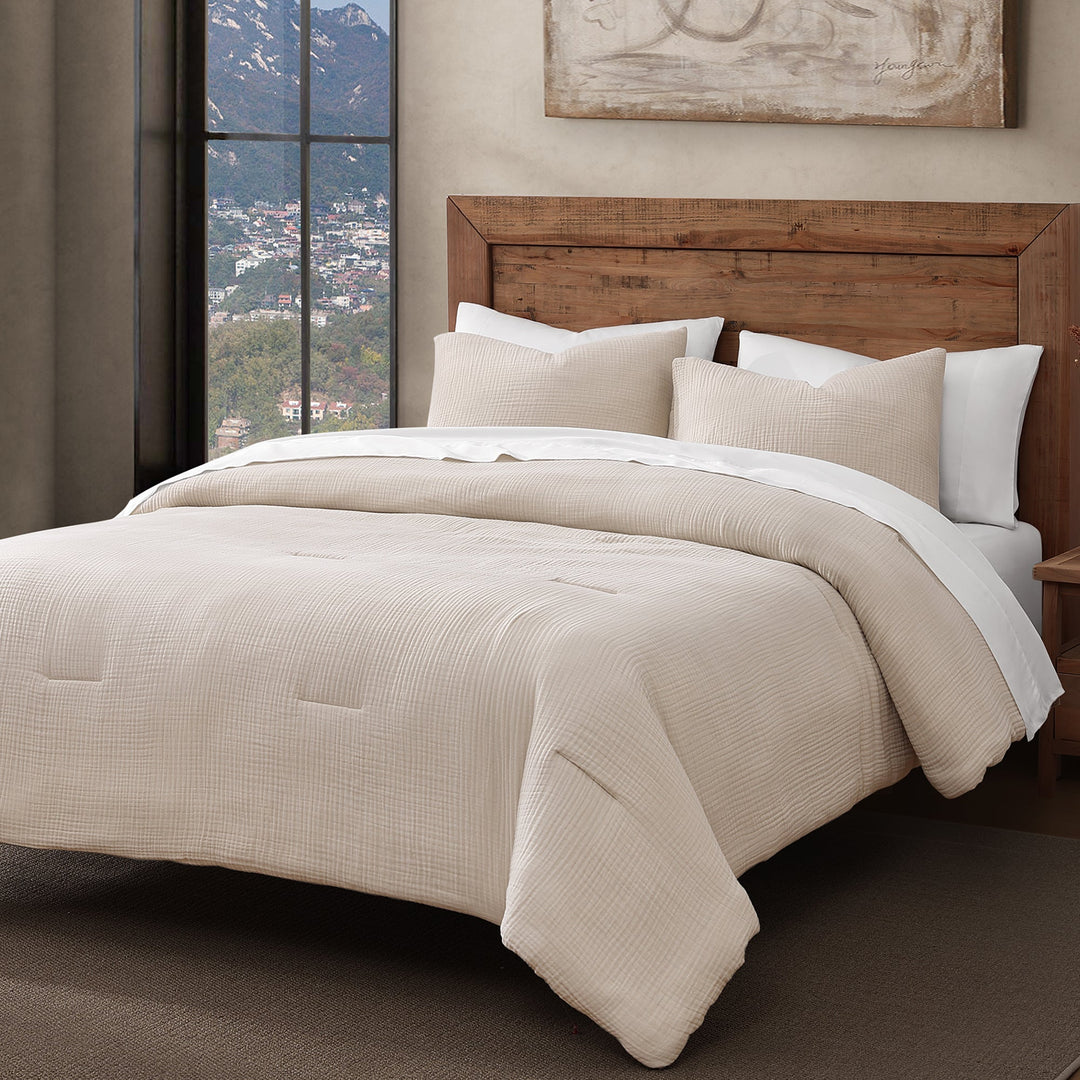 Voile cotton comforter set in sable on a bed with pillows in a room with a window view of mountains.