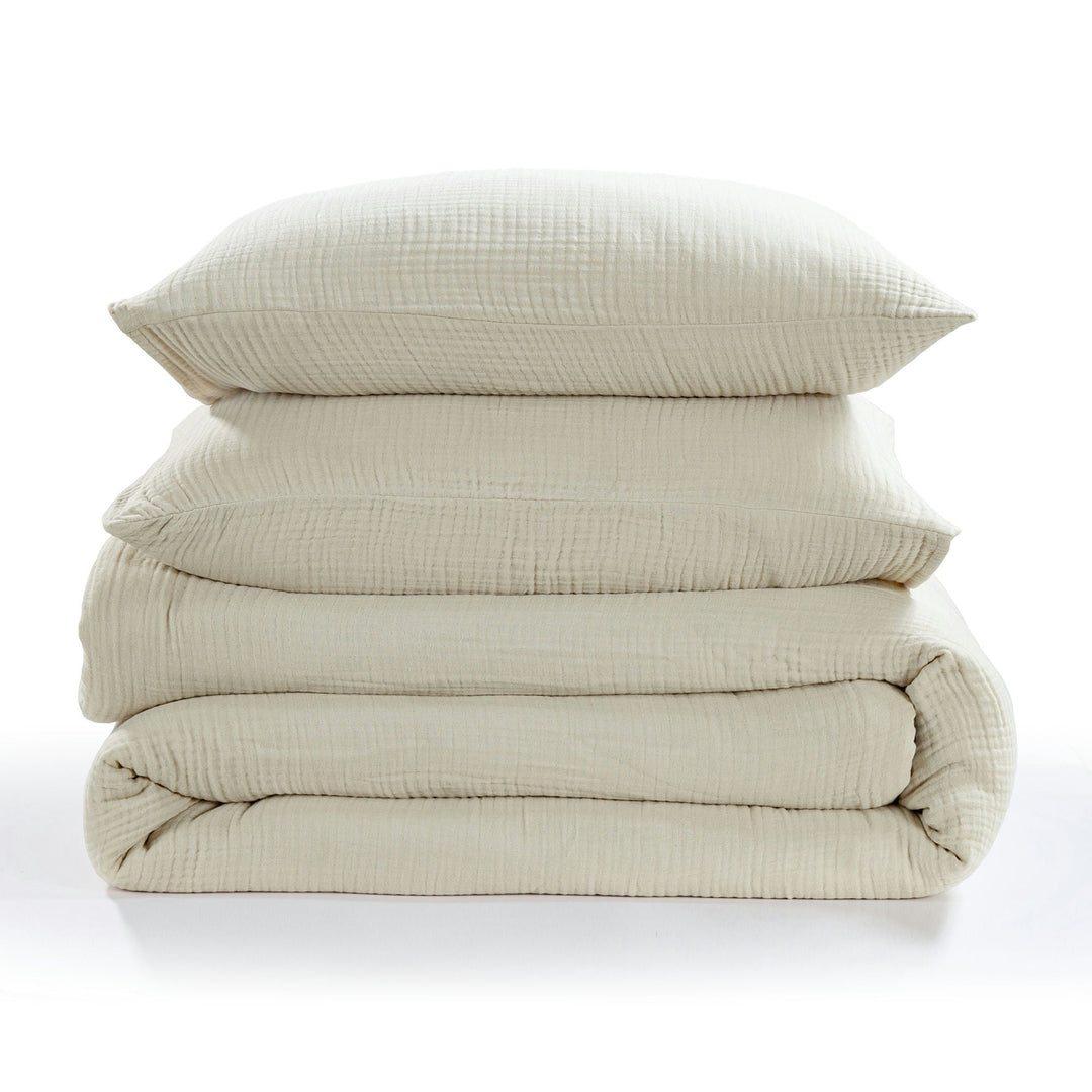 Stack of voile cotton bedding set in sable with a pillow on a white background