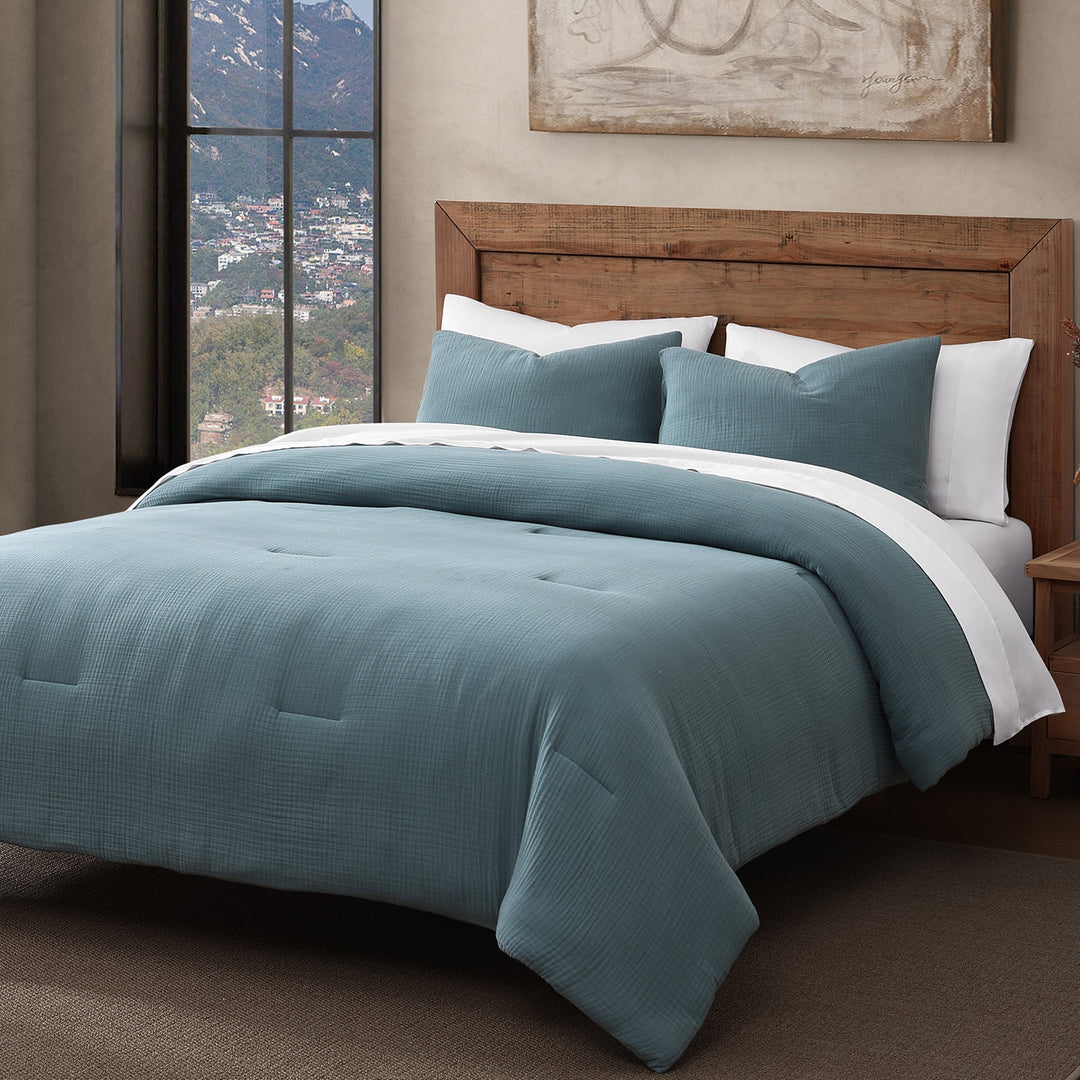 Voile cotton comforter set in storm blue with white sheets on a natural wood bed frame