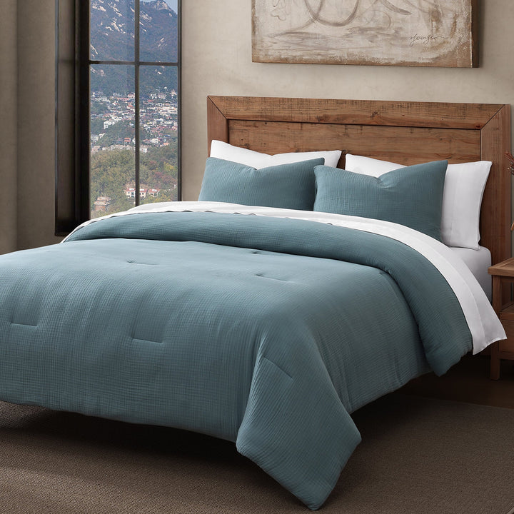 Voile cotton comforter set in storm blue with white sheets on a natural wood bed frame