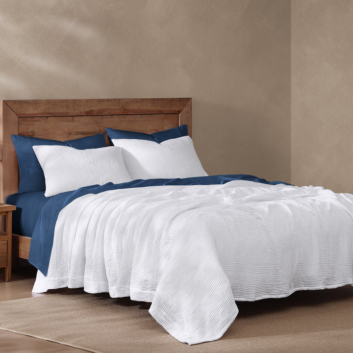 voile cotton blanket in white and blue sheets against a beige wall